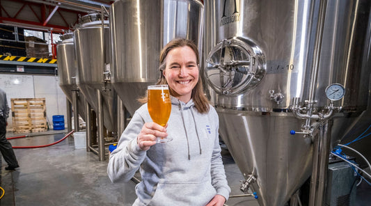 Sonja Mitchell holding a glass of beer in a brewery setting