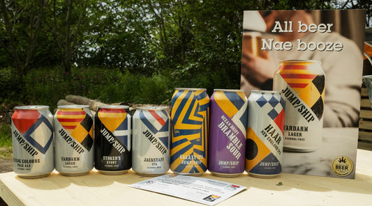 A selection of Jump Ship non-alcoholic beers on a bar in an outdoor setting front view