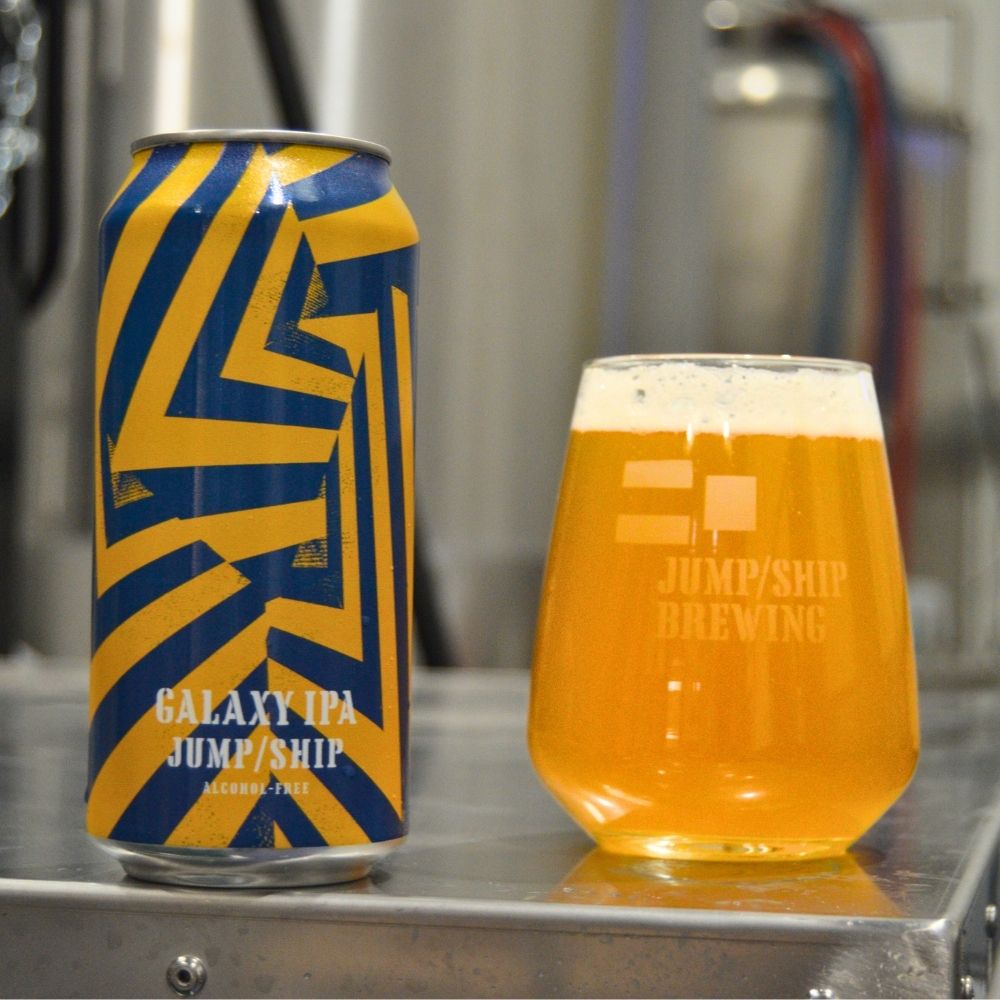 Can and glass of Dazzle Ship Galaxy IPA from Jump/Ship Brewing on a metal surface.