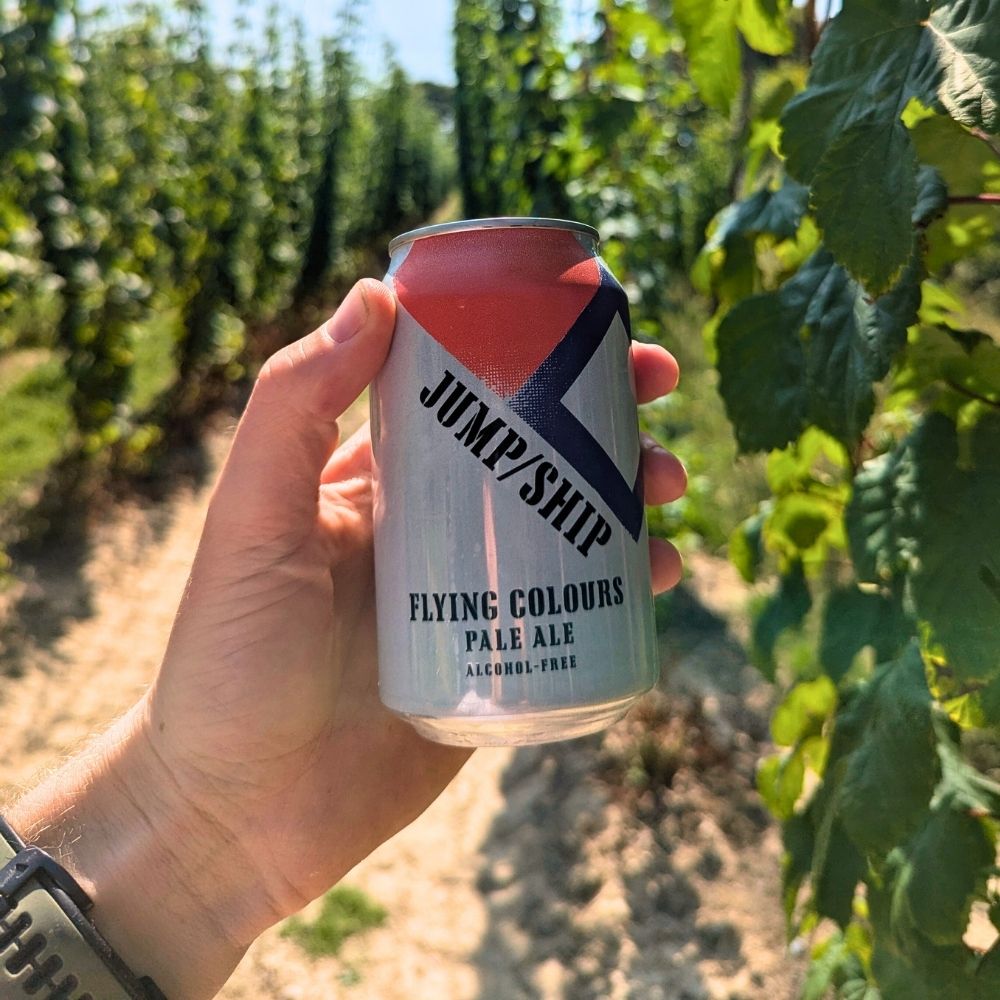 Hand holding a can of Jump/Ship Flying Colours Pale Ale in a hop field setting