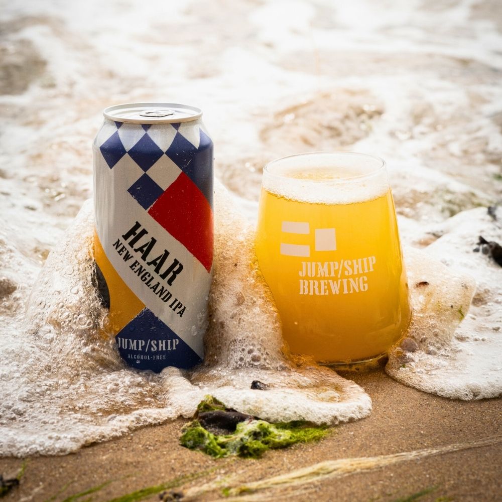 Can and glass of HAAR New England IPA from Jump/Ship Brewing on a beach.