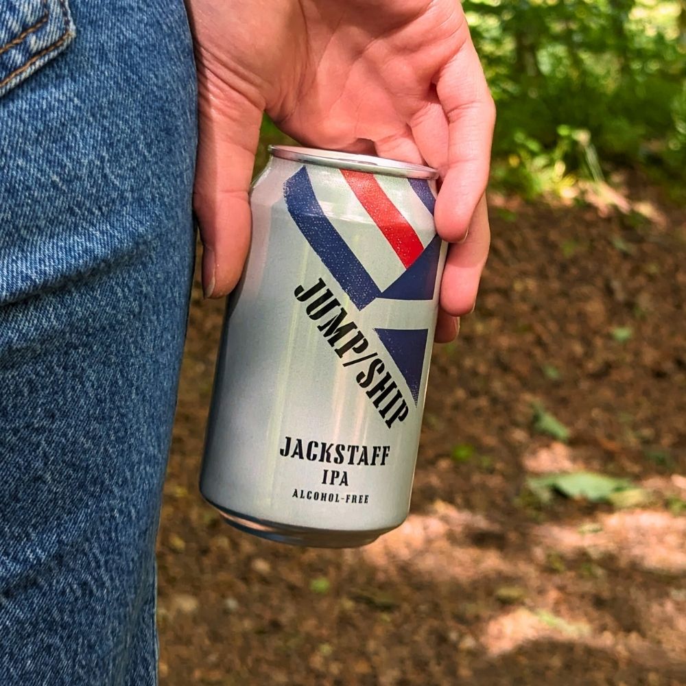 Hand holding a can of Jackstaff IPA with a blurred natural background