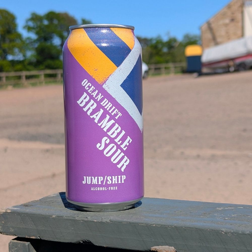 Purple can of 'Ocean Drift Bramble Sour' by Jump/Ship on a wooden surface with a blurred outdoor background.