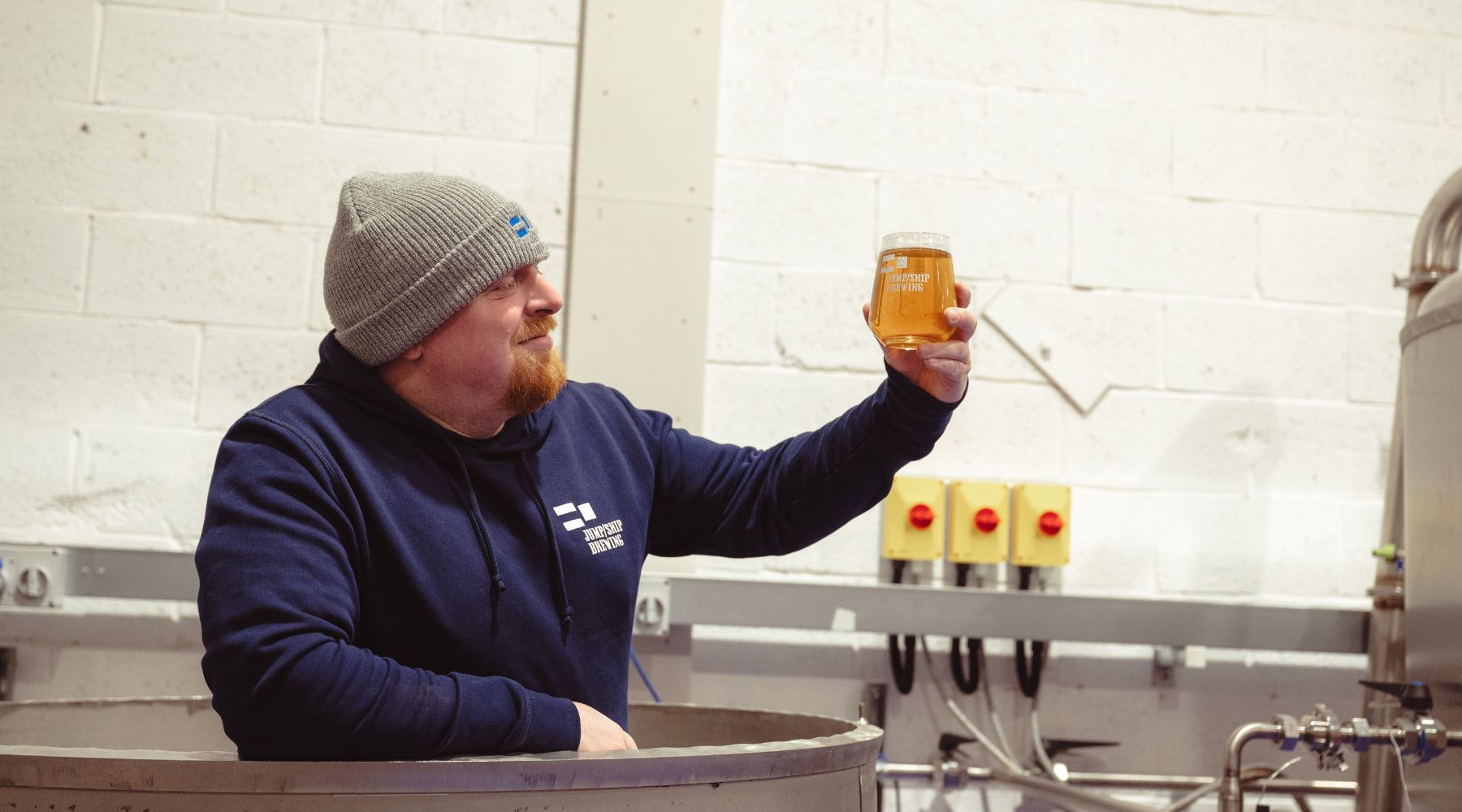 Jump Ship's Head Brewer Peter Sharp holding a glass of beer in a mash tun