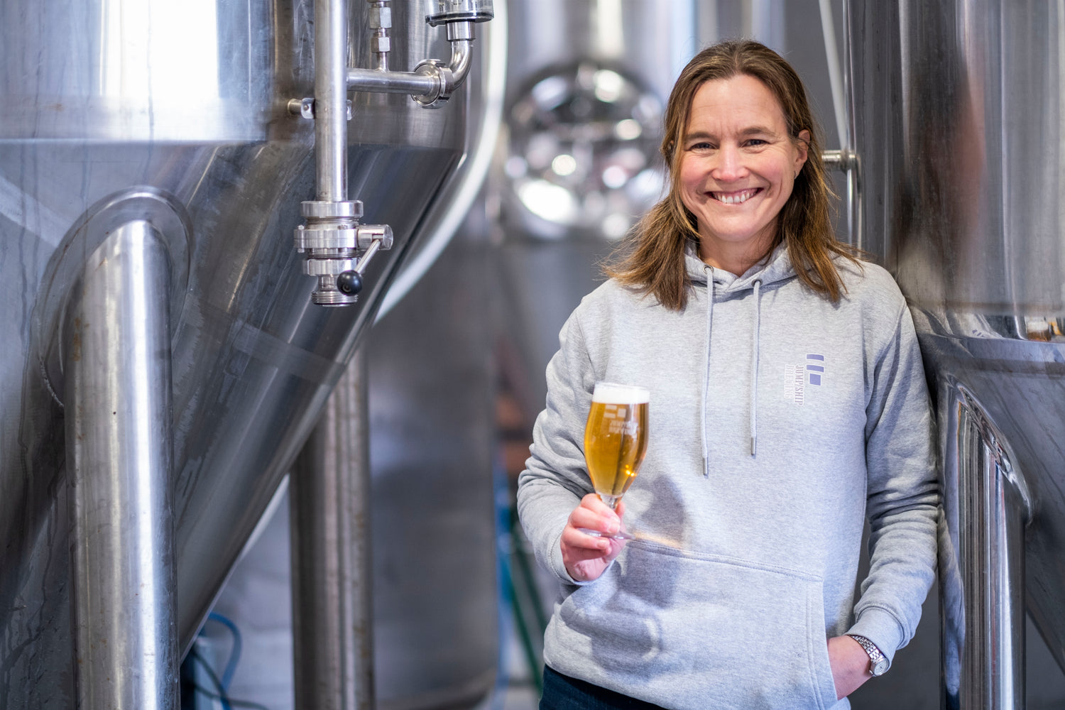 Sonja Mitchell stood in alcohol free brewery with glass of alcohol-free beer