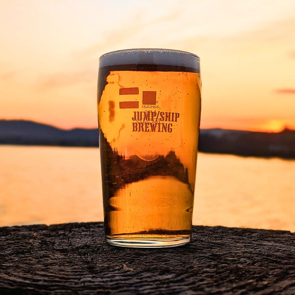 Pint of beer from Jump Ship Brewing with a sunset background