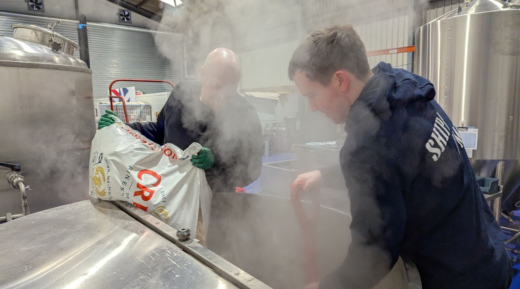 Two people mashing in at Jump Ship's brewery with steam 