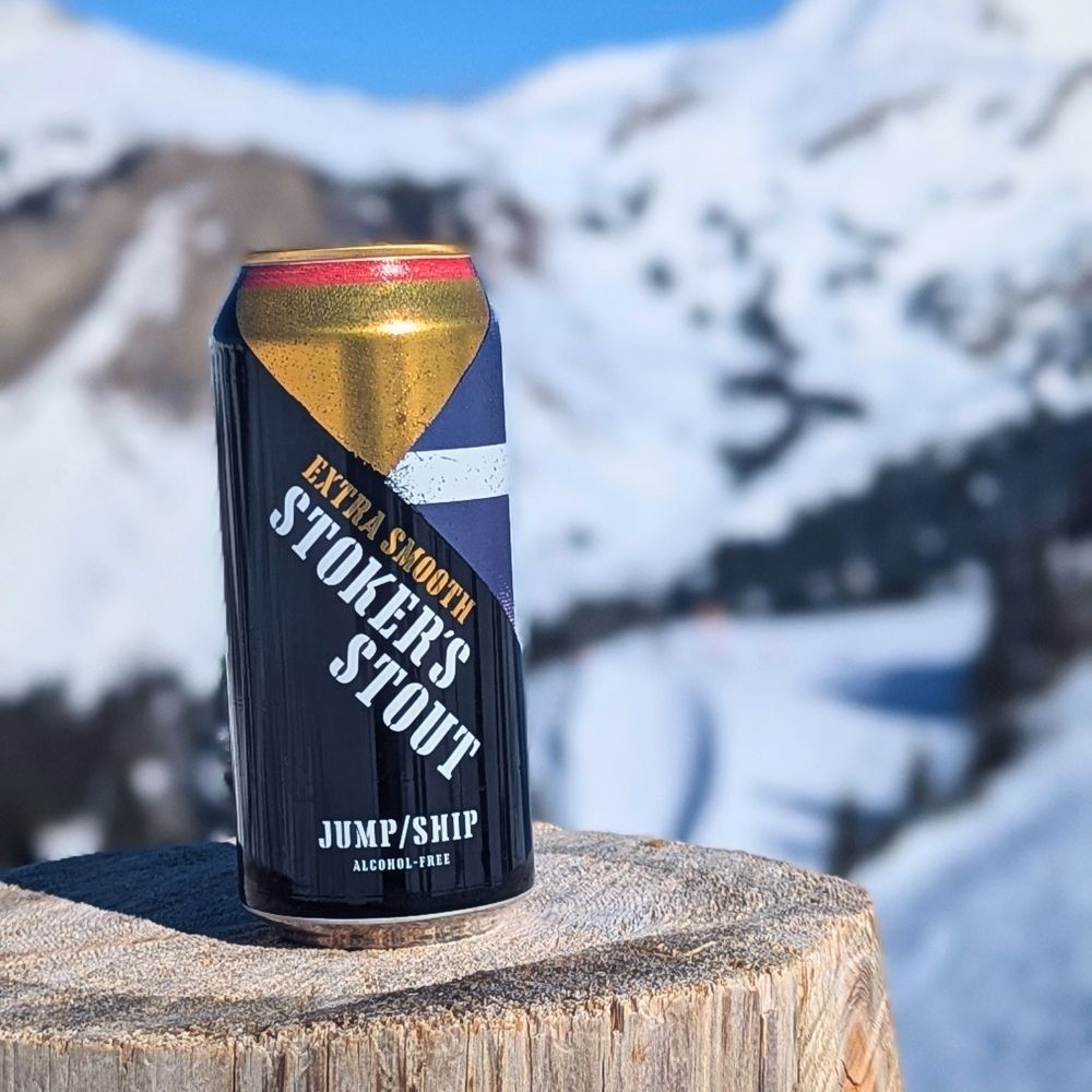 Can of Stokers Extra Smooth Stout on a wooden surface with a mountainous background