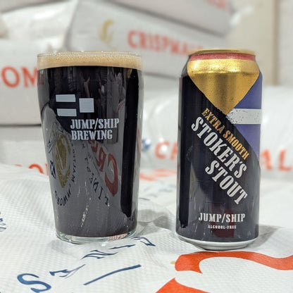 Glass pint and can of Jump/Ship Brewing Stokers Extra Smooth Stout on a pile of malt sacks